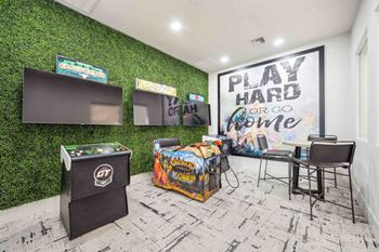 a game room with green turf wall and white brick flooring